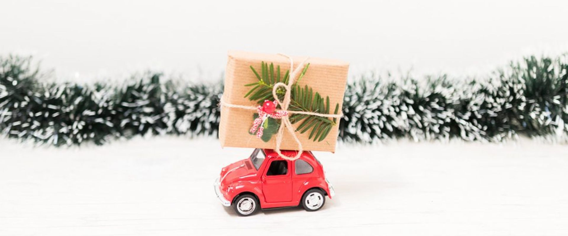 Mini auto rojo con un regalo navideño en el techo, simbolizando viajes y festividades de fin de año en Guatemala.